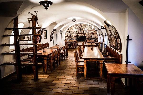 the inside of a restaurant with wooden tables and benches in front of an arched doorway