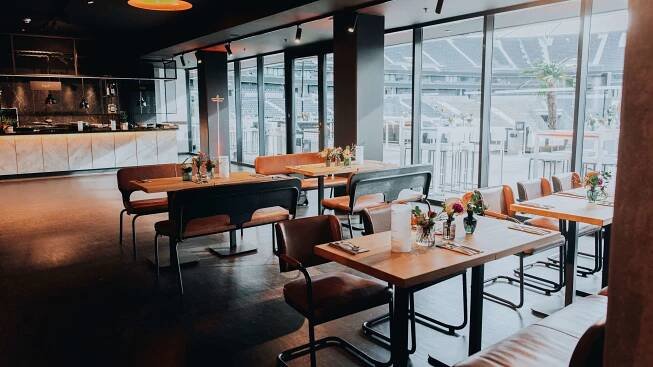 Moderne Lounge mit gedeckten Tischen und Blick auf das Stadioninnere durch große Fenster.