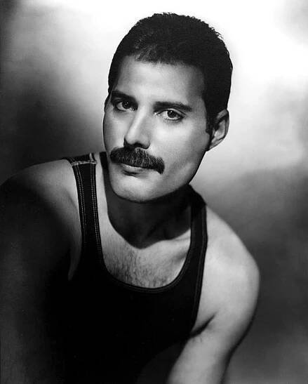 black and white photograph of a man with a moustache wearing a tank top