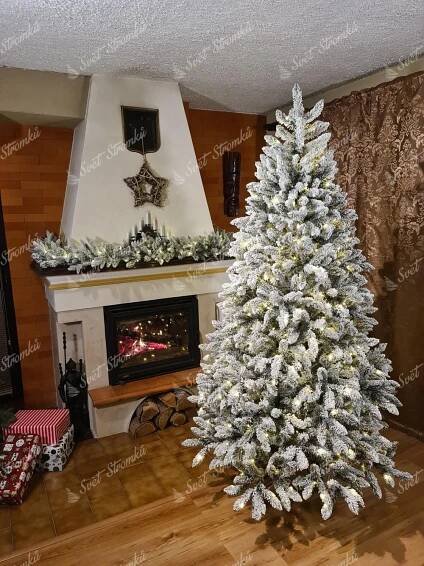 a white christmas tree sitting on top of a hard wood floor next to a fire place