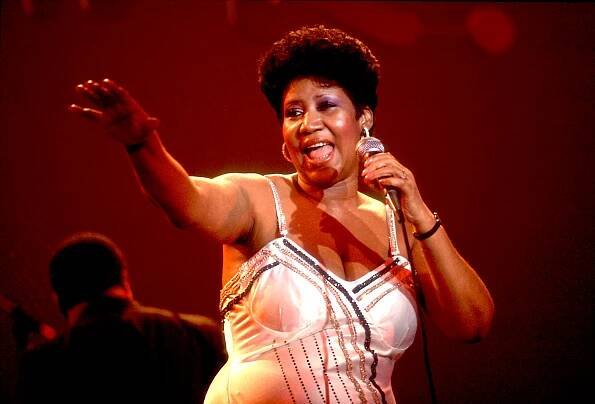 Singer on stage with microphone, wearing an elegant, sequined dress, reaching out to the audience while performing energetically