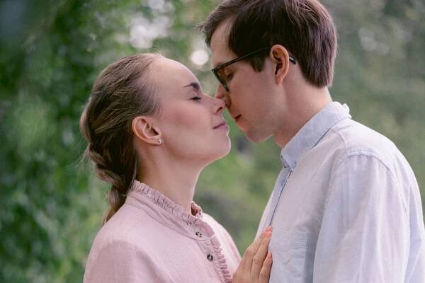 Romantic couple in soft pink and white share tender moment outdoors.