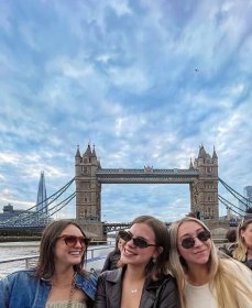 three students pose in front of a bridge in London
