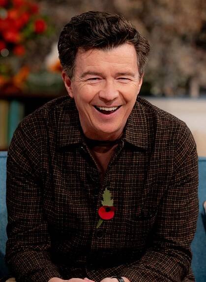 a man wearing a plaid shirt has a poppy pin on his chest