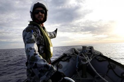 Able Seaman Boatswain's Mate Cameron Grant directs the coxswain of the Rigid Hull Inflatable Boat of HMAS Perth during a flight MH370 search.