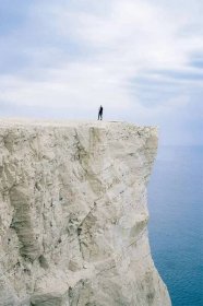 The image shows a girl standing on top of one of the Seven Sisters Cliffs.