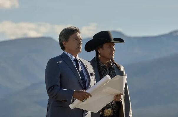 A man holds a folder in his hands while standing next to someone else.