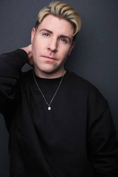 Headshot of actor and hair and makeup artist Jesse Johnson in a black shirt with silver necklace
