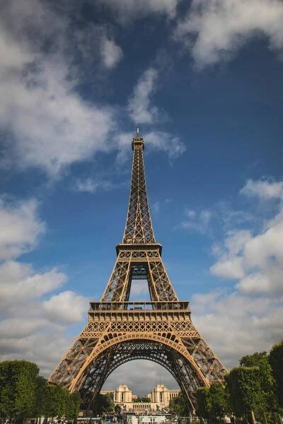 Free A stunning view of the Eiffel Tower with a backdrop of blue sky and fluffy clouds, captured in Paris. Stock Photo
