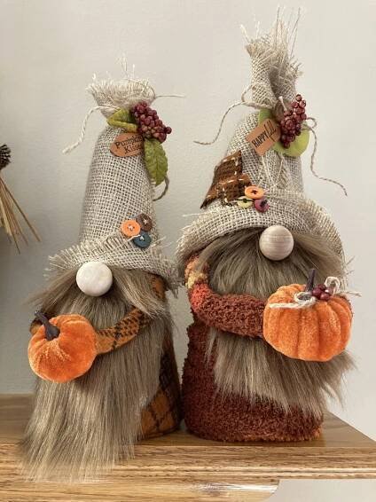 two small scarecrows are sitting on top of a shelf with pumpkins and other decorations