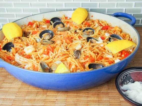 fideua (Catalan pasta paella) in pan with lemon slices around side