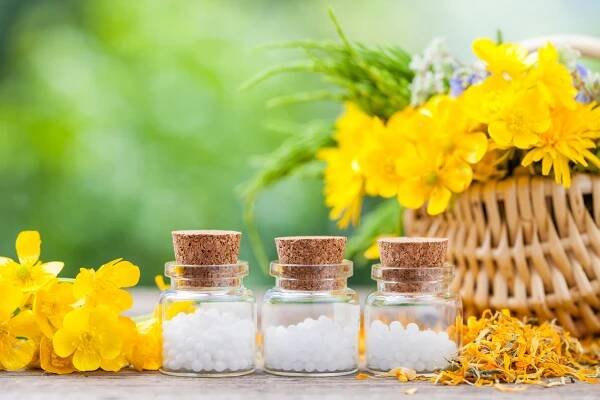 Láhve homeopatie globule a zdravé bylinky v proutěném pružin — Stock obrázek