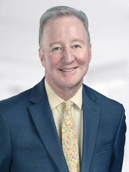 A man in a suit and tie is smiling for the camera.