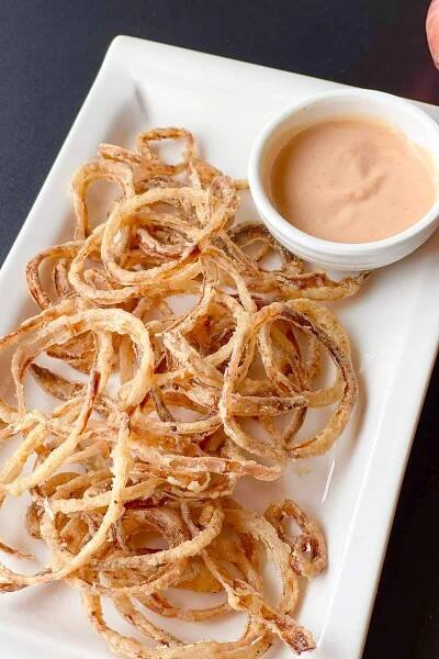 Crispy fried onion rings on a white rectangular plate.