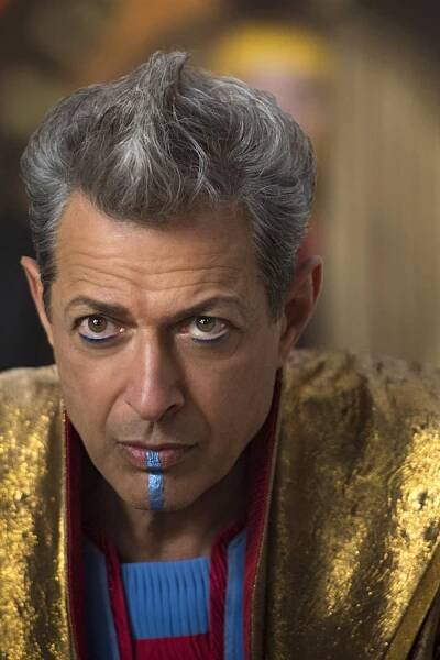 a close up of a person wearing a gold jacket and blue eyeliner with a red stripe around his mouth