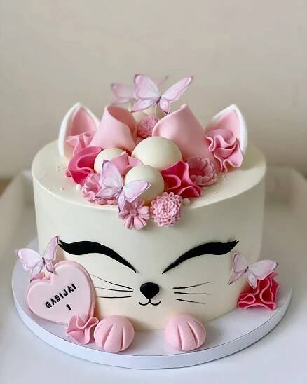 a white cake with pink flowers and butterflies on it's face is sitting on a plate