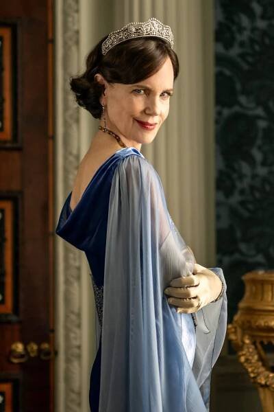 Elizabeth McGovern, the actress who plays Lady Cora in the “Downton Abbey” franchise is posing in a diamond tiara and a blue dress with translucent fabric draped down her arms.