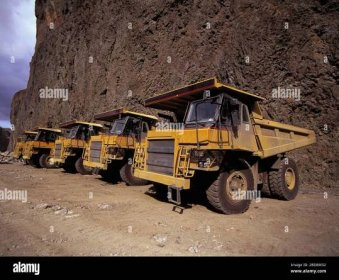 yellow dump trucks parked at side of a cliff Stock Photo