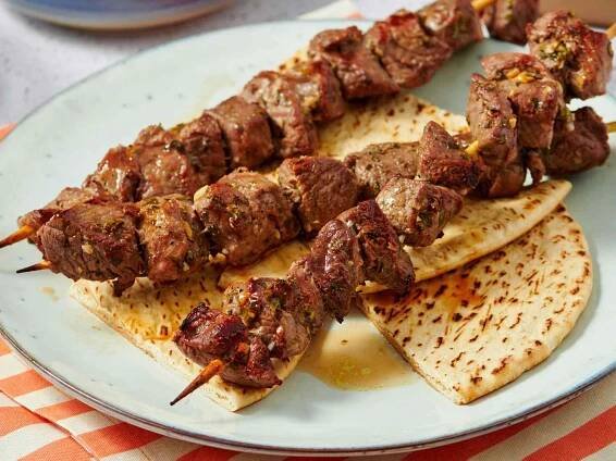 Lamb souvlaki skewers served over pita bread