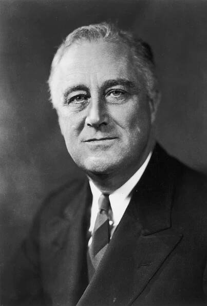 A historical portrait of a man in a suit with a tie, looking directly at the camera with a neutral expression