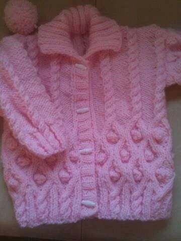 a pink knitted sweater with pom - poms