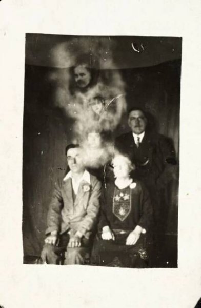 photograph of seated family group showing spirit-like apparitions and faces