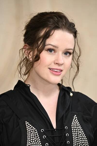Ava Philippe with brown hair in a black top smiling