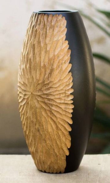 a black and gold vase sitting on top of a table next to a potted plant