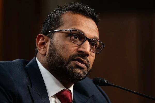 A portrait of Kash Patel in front of a microphone.