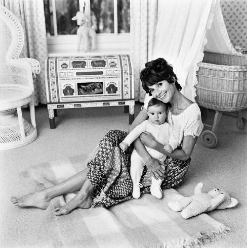 A woman sitting on the floor of a nursery with her baby in 1971