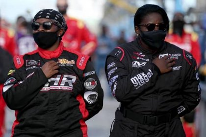 Crew members Brehanna Daniels and Dalanda Ouendeno of the #74 Covert Scouting Cameras Chevrolet stand on the grid during the national anthem.