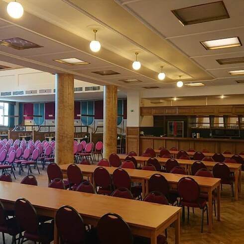 Sál v Besedě připravený na konferenci nebo kulturní akci s barem a řadami červených židlí