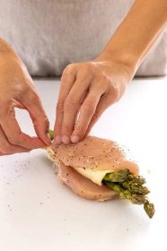 Person sealing the edge of a stuffed chicken breast with toothpicks.
