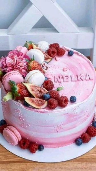 a pink cake decorated with fresh fruit and flowers