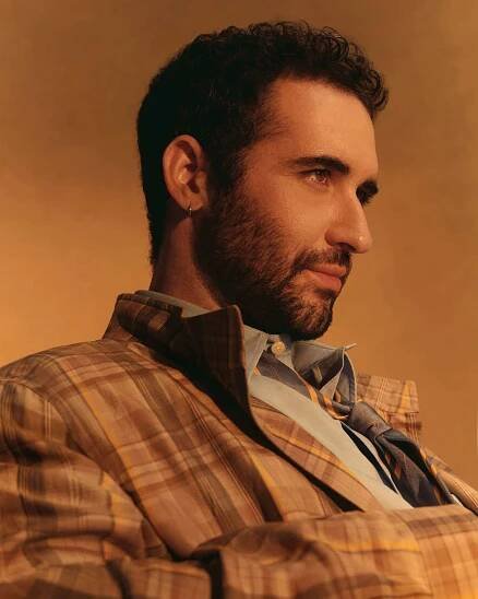 Jordan Firstman looking off camera in a plaid jacket