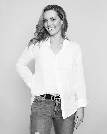 Black and white professional portrait of someone in a classic white button-down shirt and jeans with a designer belt.