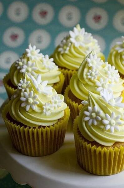 several cupcakes with white frosting and flowers on them sitting on a plate