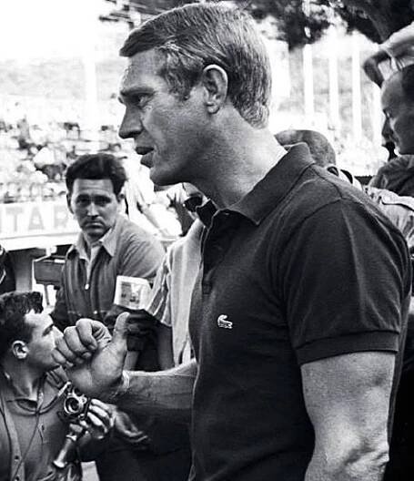 a black and white photo of a tennis player talking to an official in front of a crowd