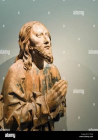 Medieval Wooden sculpture of Christ Praying. A worn statue of a praying Christ figure, its paint flaking off to show the wood Stock Photo