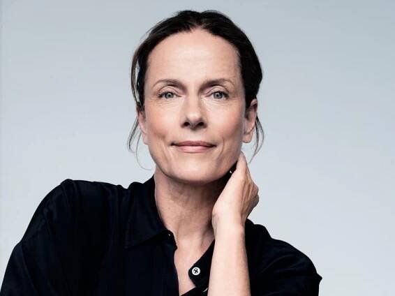 Claudia Michelsen lächelt in die Kamera. Sie trägt ein schwarzes Hemd und hat das Haar hochgesteckt.