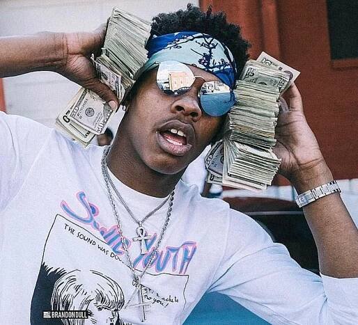 Lil Baby Holder Money in both hands while wearing sunglasses and bandana on forehead