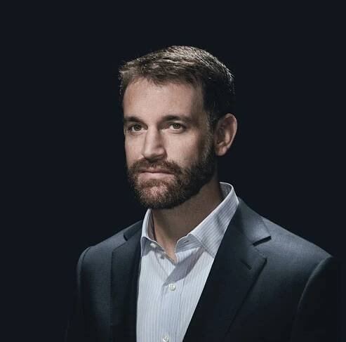 Image may contain Face Human Person Clothing Overcoat Apparel Coat Suit Beard and Tuxedo