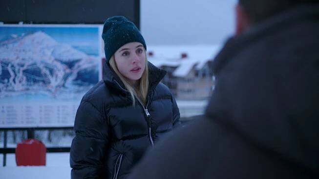 Hanna wearing a woolly hat with a puffer coat looking at someone off-camera in The &Aring;re Murders.
