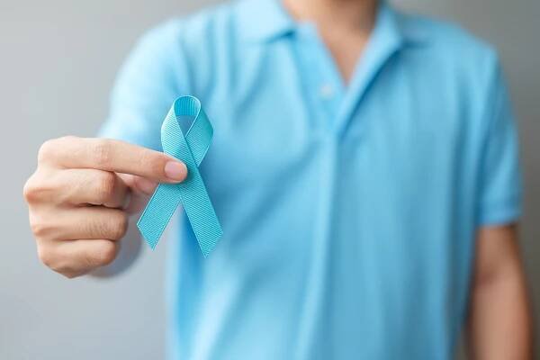 Man in blue shirt with hand holding Blue Ribbon
