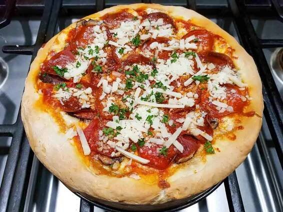 shredded parmesan cheese and fresh parsley sprinkled on top of a baked deep dish pizza.