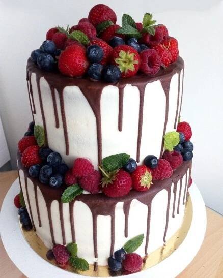 a three layer cake topped with berries and chocolate