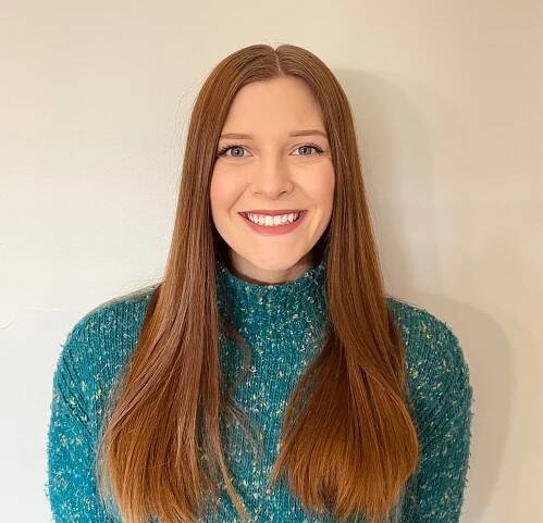 a woman with long brown hair wearing a blue sweater