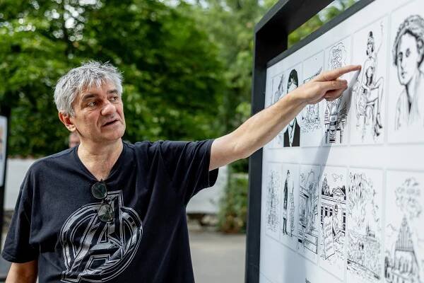 Karikaturista Štěpán Mareš u panelů svých prací na Smíchově.