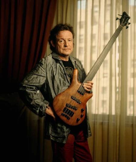 Jack Bruce pictured holding a bass guitar in a hotel room