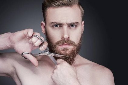 Shirtless chlap řezání vousy s nůžkami — Stock fotografie